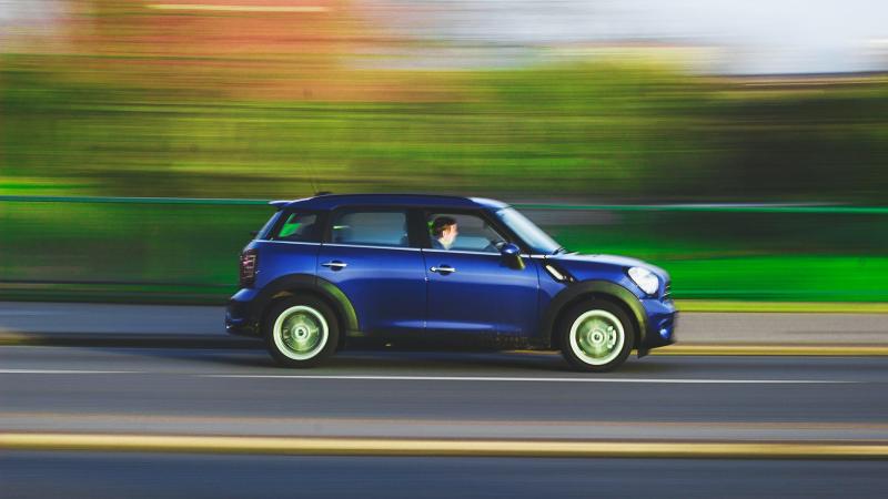 Blue car driving fast down a highway