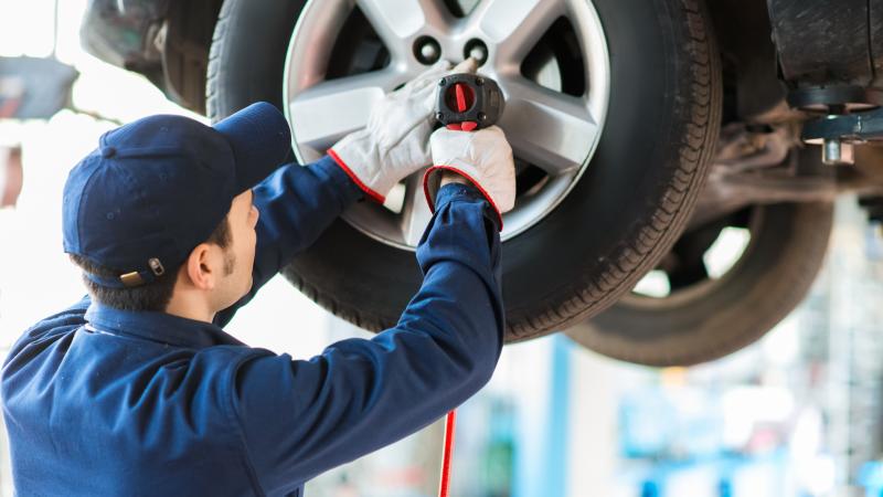 Mechanician changing car wheel in auto repair shop